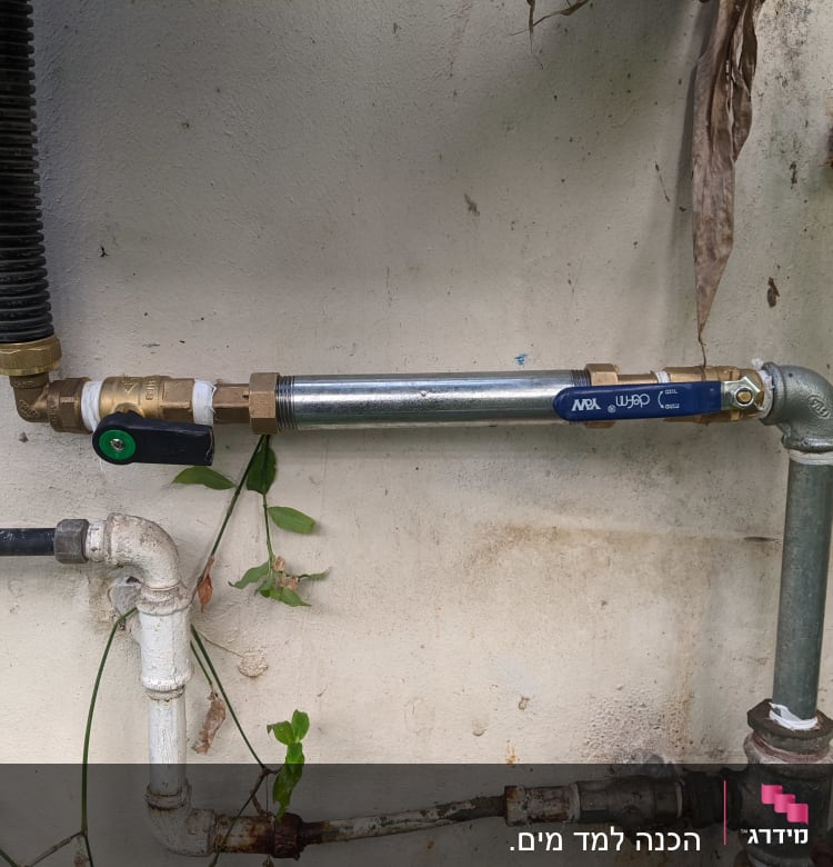 צינורות מתכת עם ברזים ומחברים על קיר חיצוני